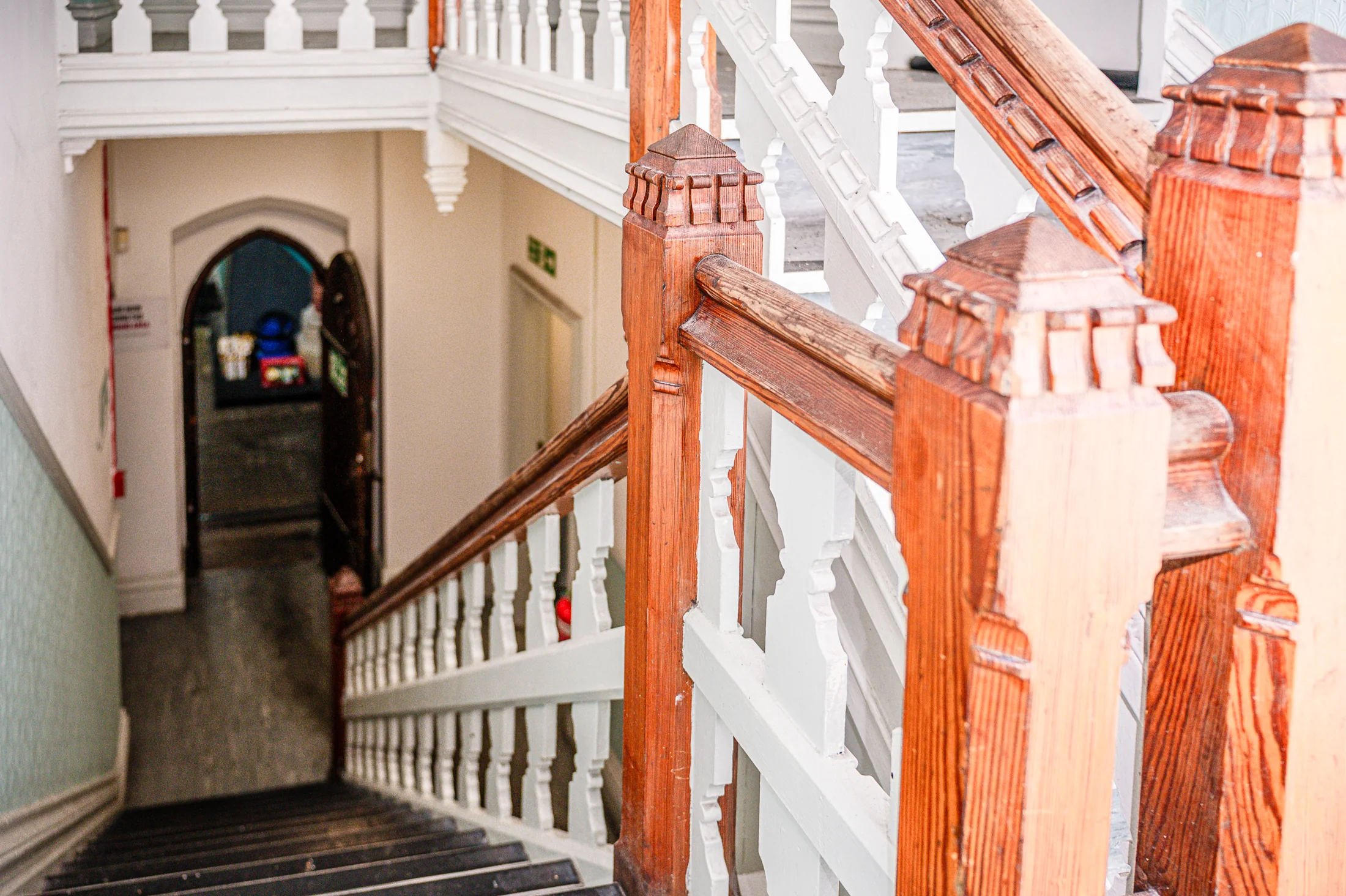 A timber staircase with painted balusters and a carved newel post