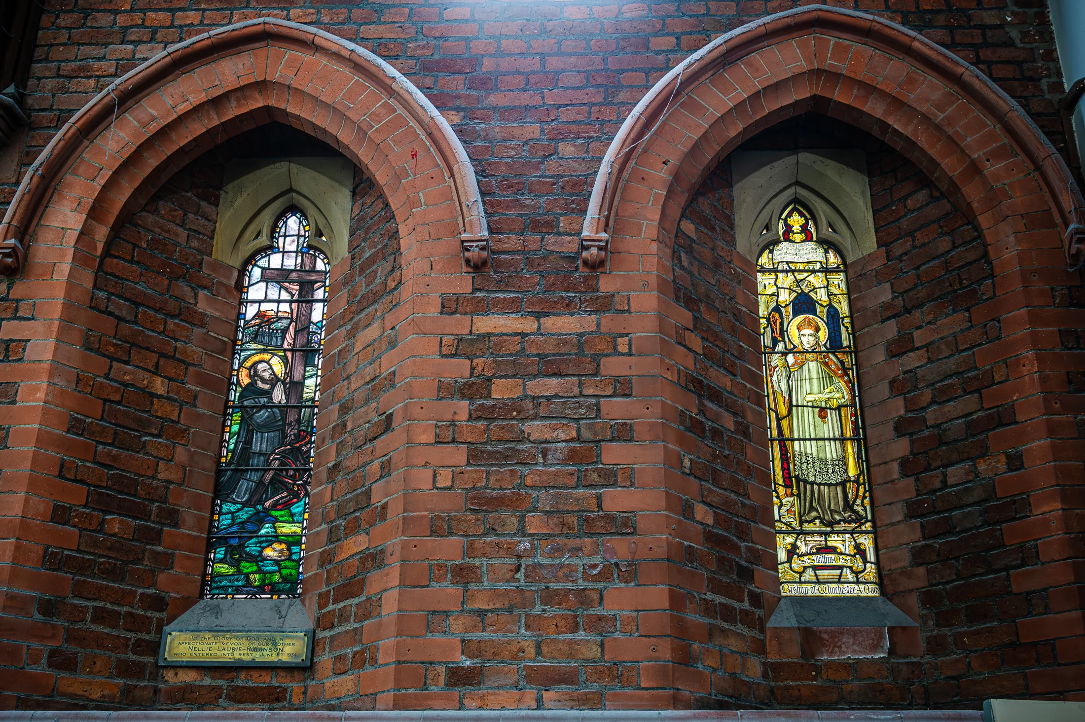 Two narrow stained-glass windows in pointed brick arches